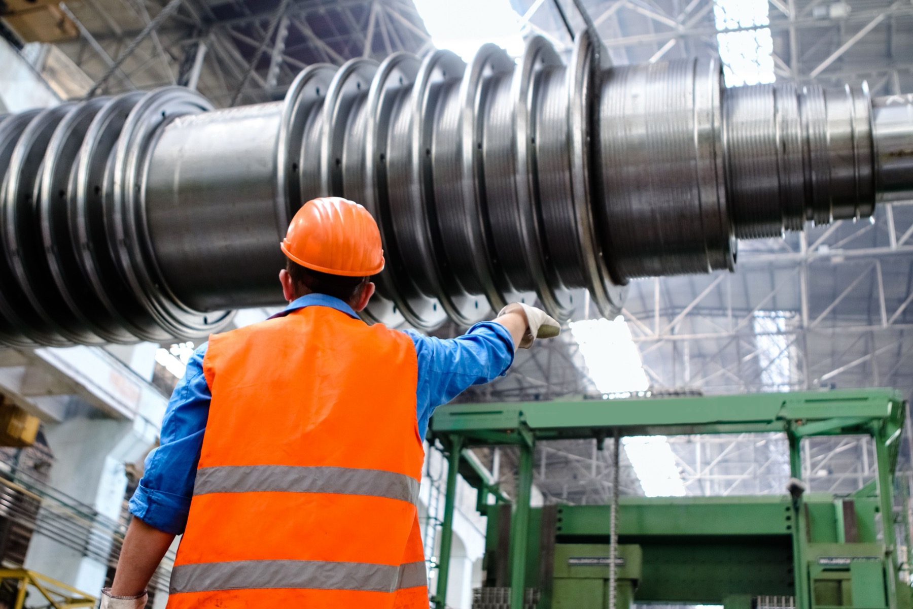 Industrial worker in high-visibility vest inspecting factory machinery